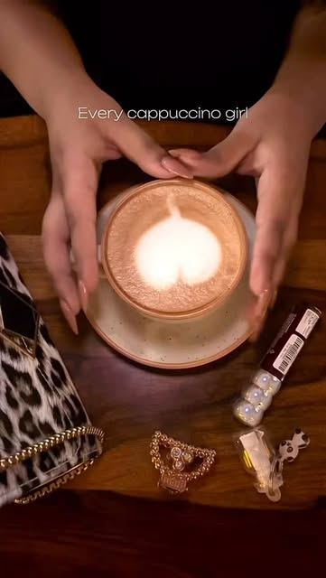 Hands around a cappuccino with heart latte art