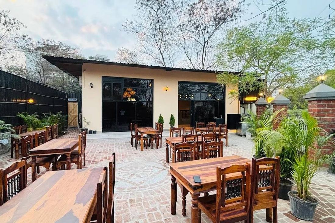 Gully Gourmet's brick-paved open courtyard with wooden tables and palms
