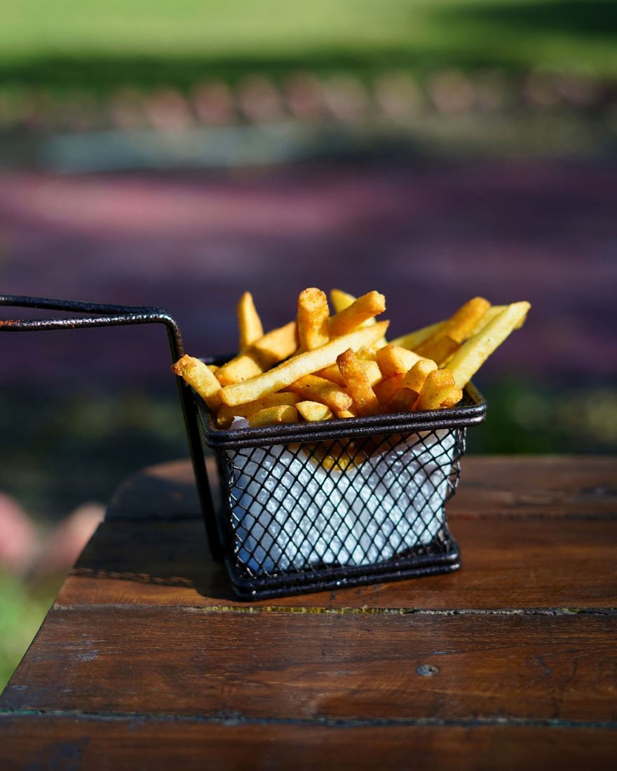Peri peri fries in a wire basket on a wooden table