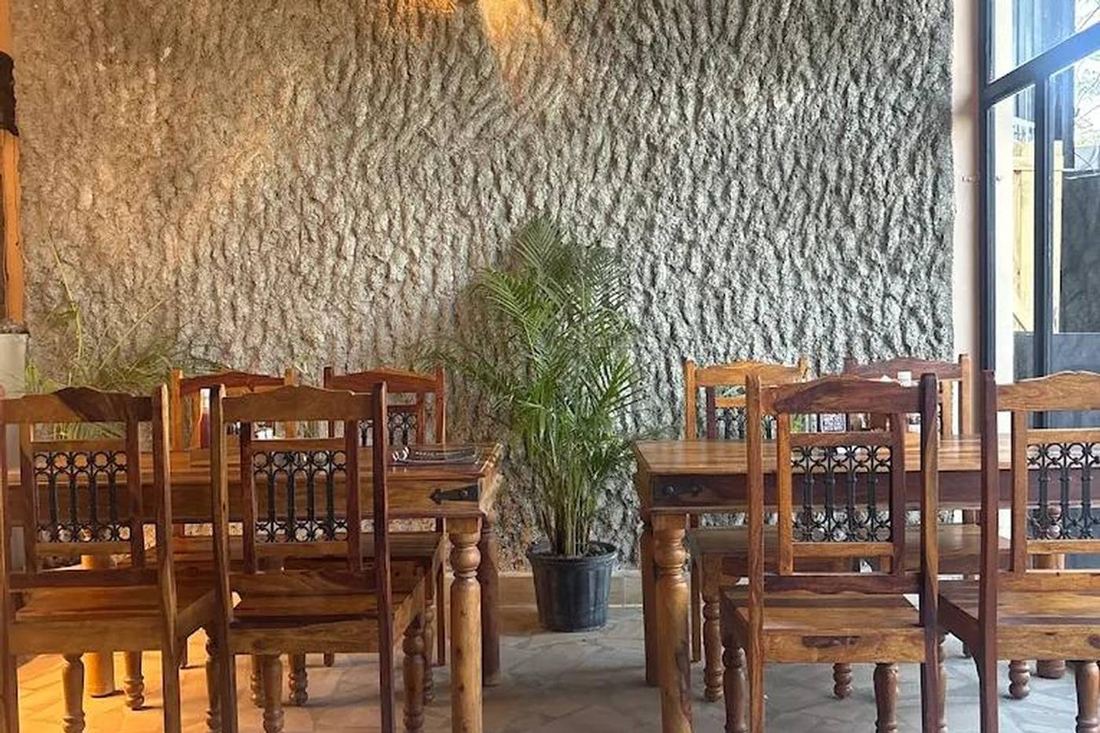 Dining area with carved wooden chairs against a textured stone wall